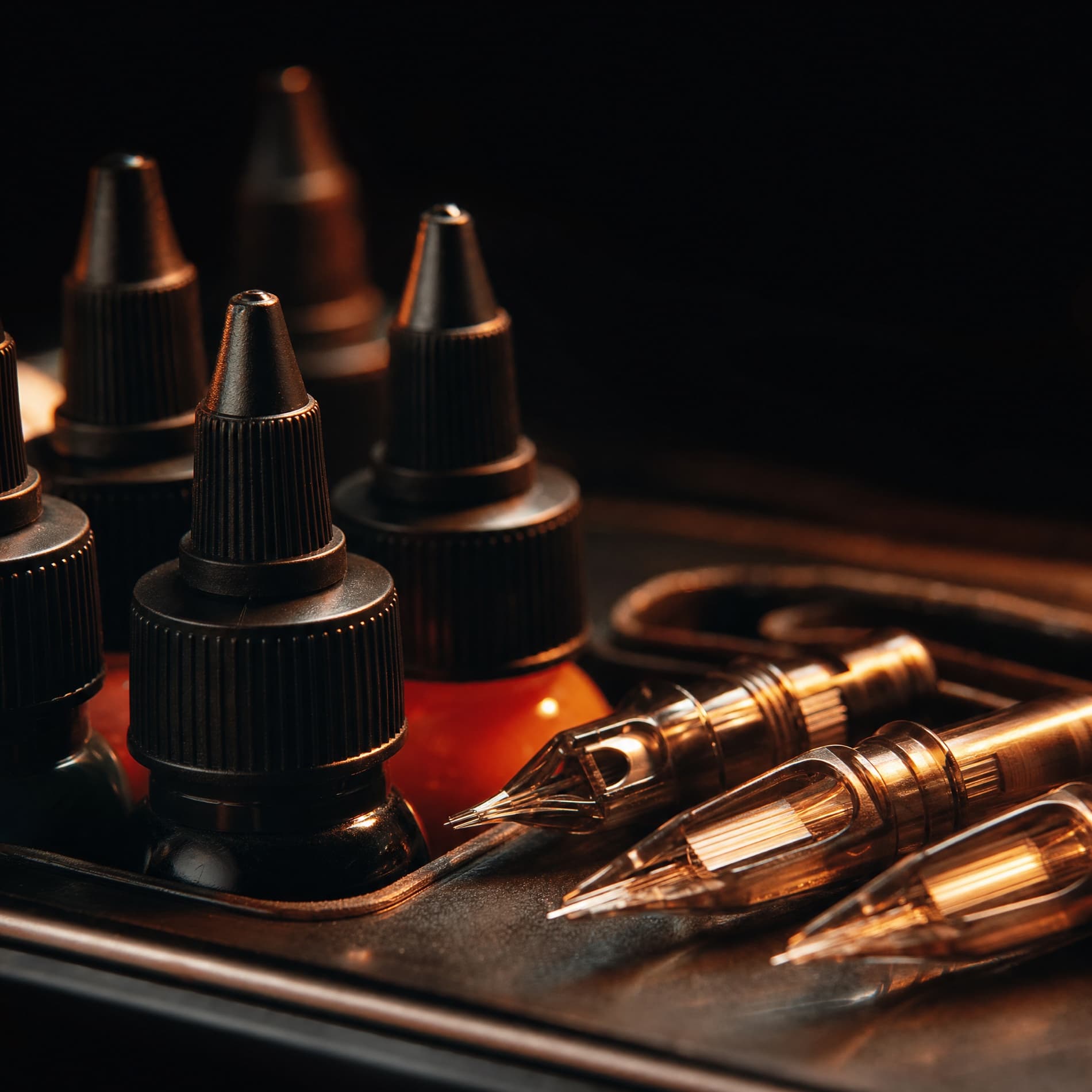 Macro of tattoo ink bottles and needle cartridges in amber light