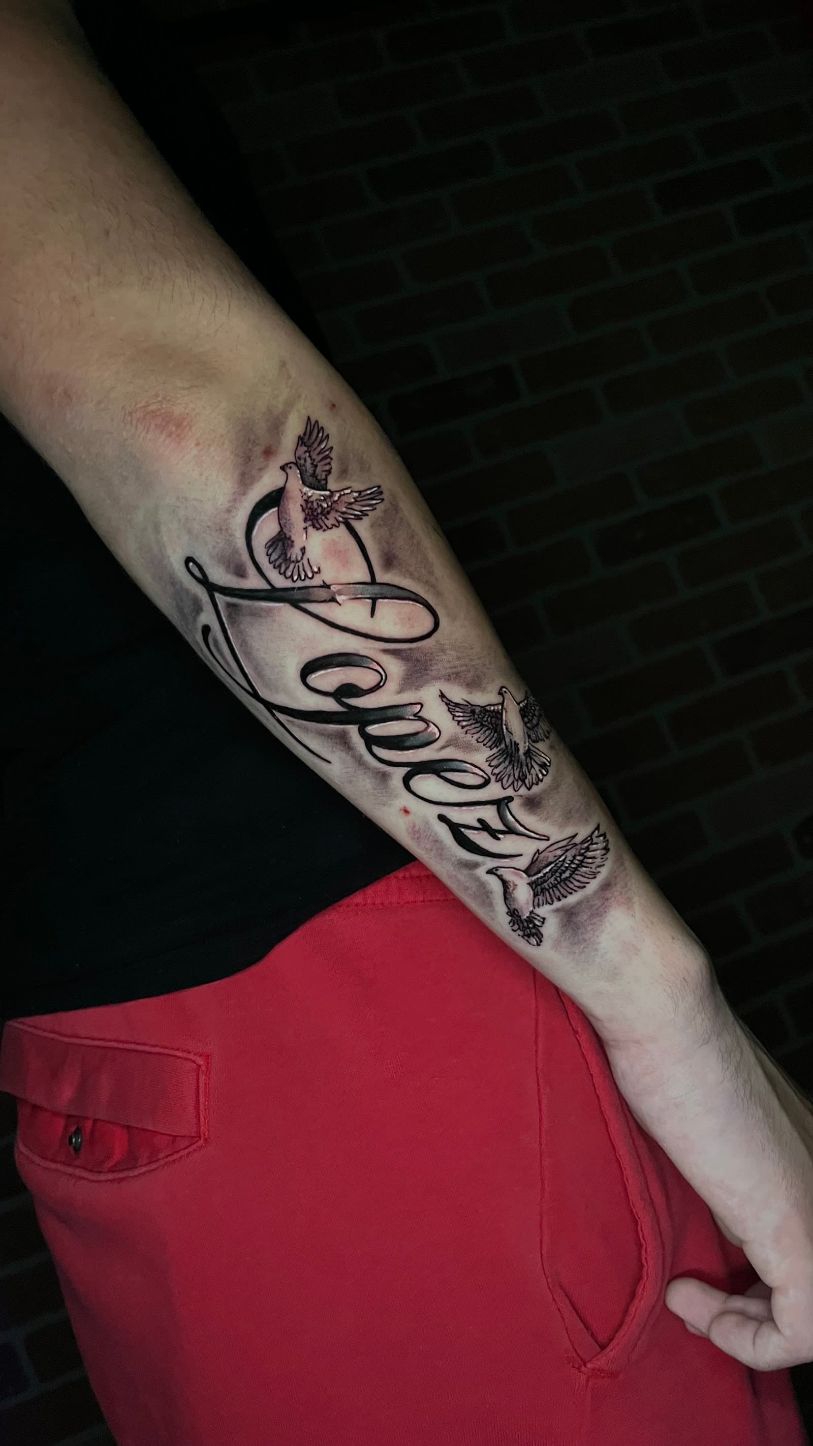 Script lettering forearm tattoo with doves