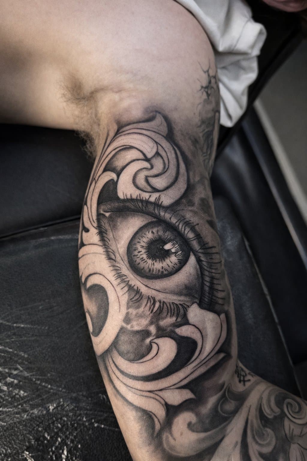 Black and grey eye and filigree ornamental sleeve on an upper arm