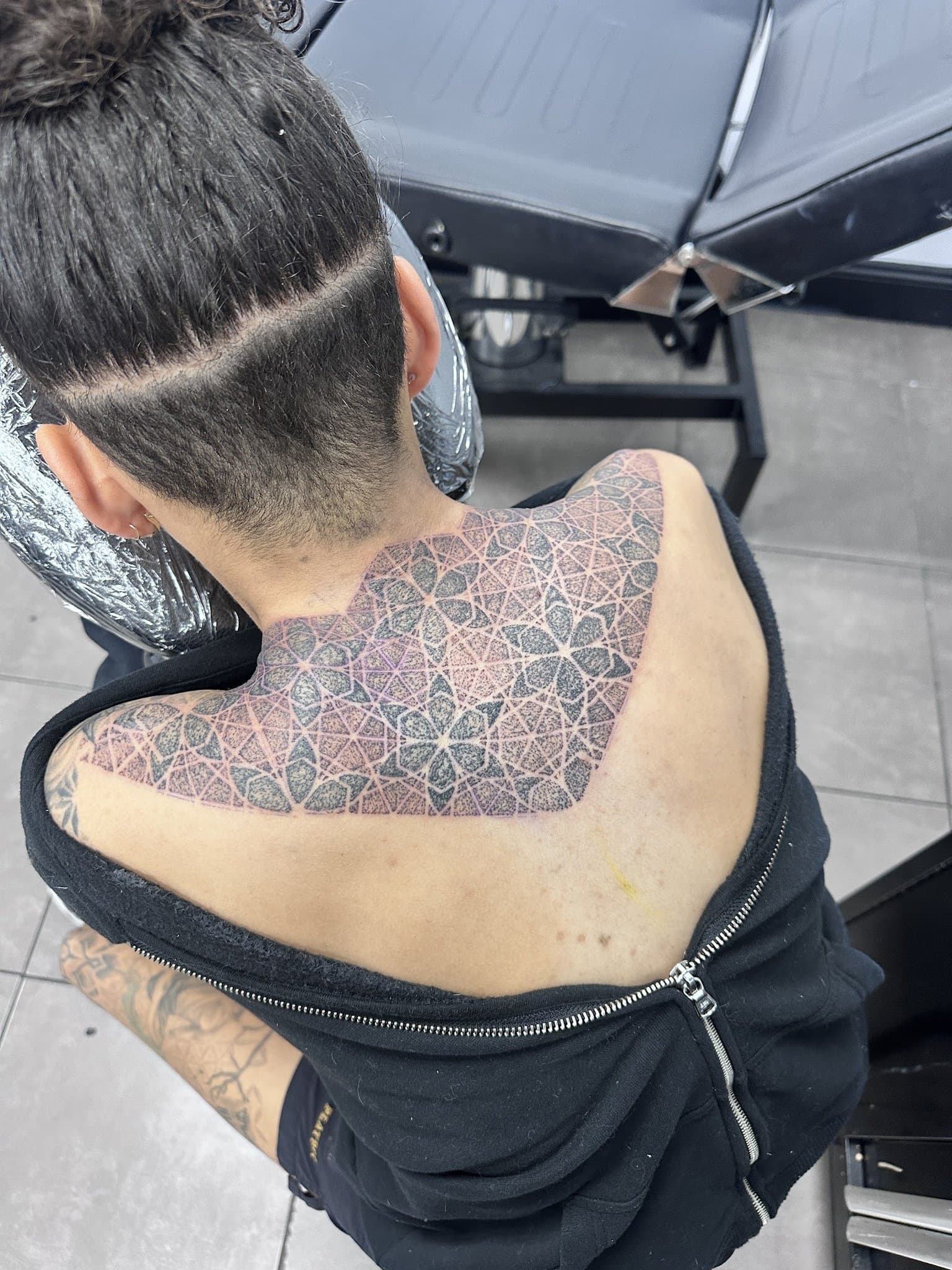 Dotwork geometric pattern across a neck and shoulder