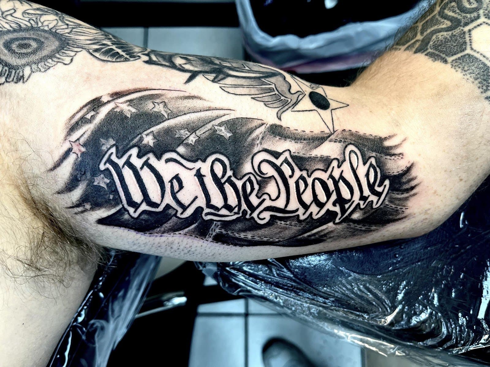 We The People script biceps tattoo