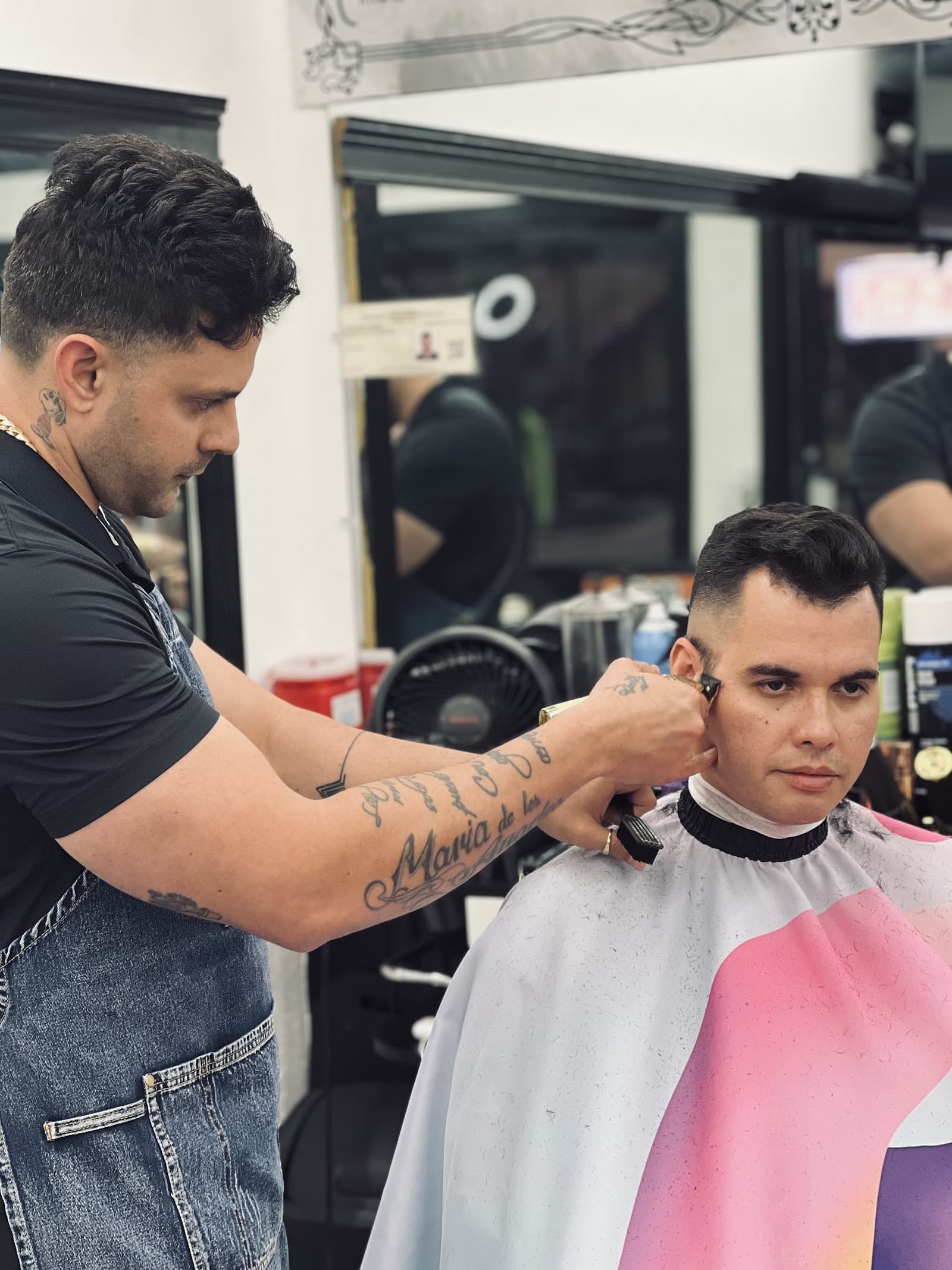 A barber lining up a client's cut in the mirrored chair area at Marah BarberShop