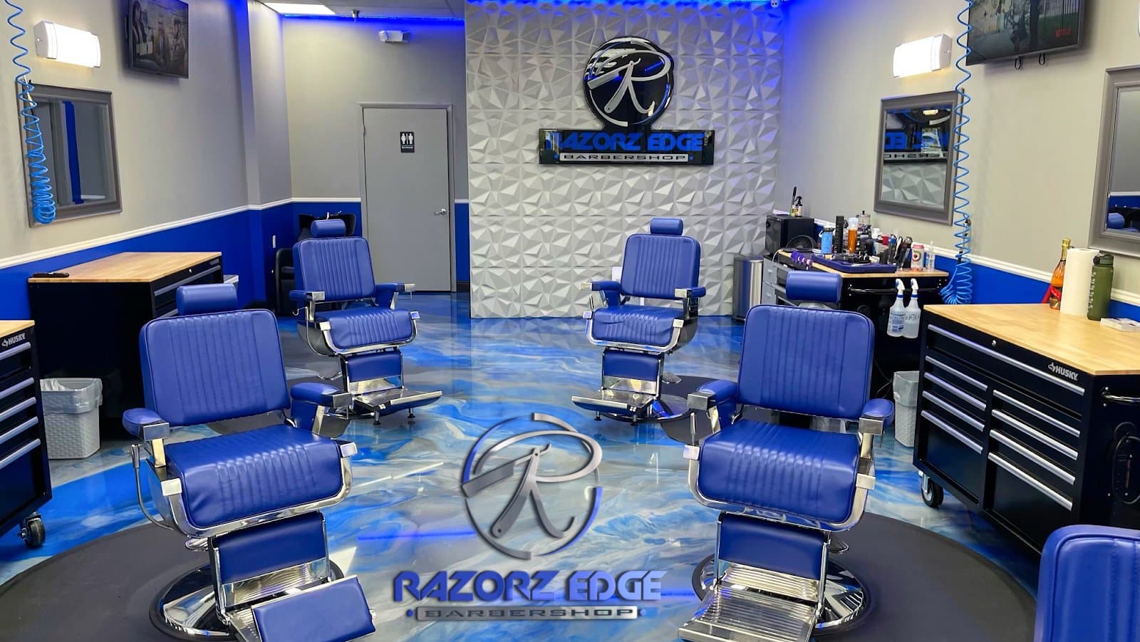 Inside Razorz Edge Barbershop — blue metallic chairs and logo wall