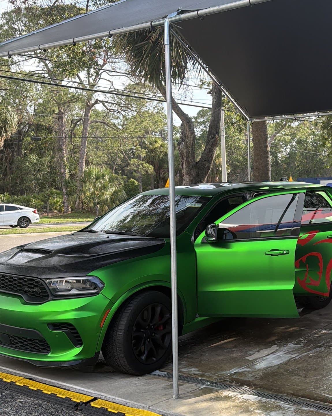 A green Dodge Durango SRT under the wash canopy at Rock's Car Spa