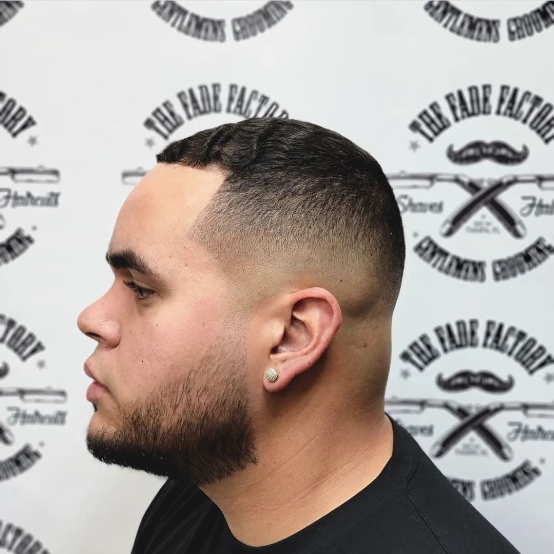 Beard and fade profile against The Fade Factory logo wall