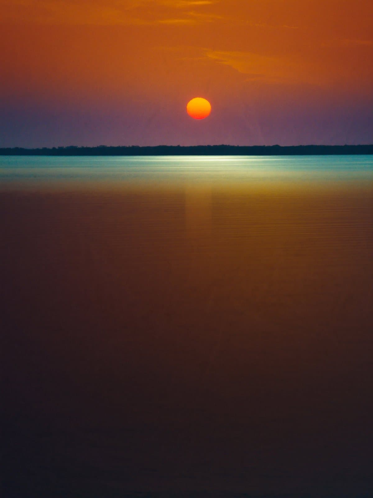 A burning orange sunset over calm Gulf of Mexico water off the Tampa coast